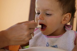 Une main nourrissant un jeune enfant